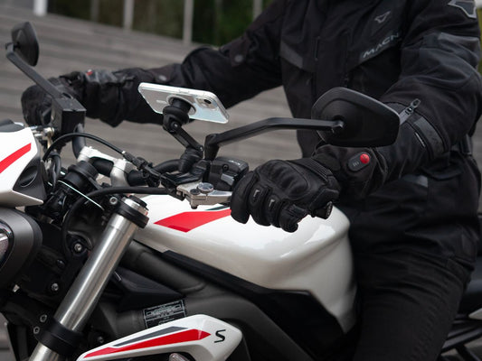 Un motociclista sonriente, listo para salir con todo su equipo, refleja la serenidad de un viaje bien preparado. Una invitación a adoptar los reflejos adecuados para conducir con confianza.
