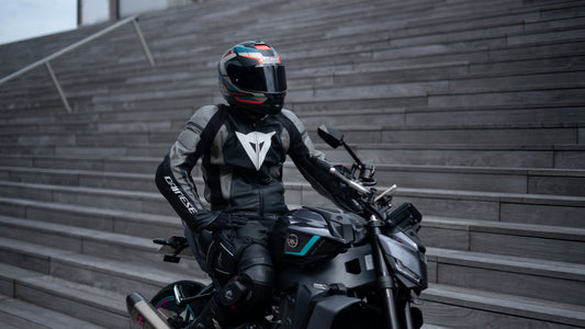 Motociclista y pasajero detenidos, sonrientes y bien equipados, representando la serenidad de un viaje preparado con Shapeheart.