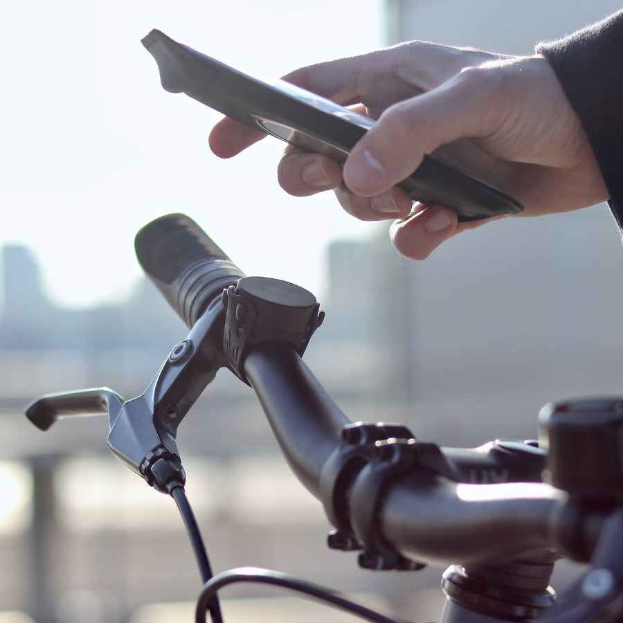 Colocación del teléfono en la funda magnética sobre el soporte fijado con una correa elástica en el manillar de la bicicleta.
