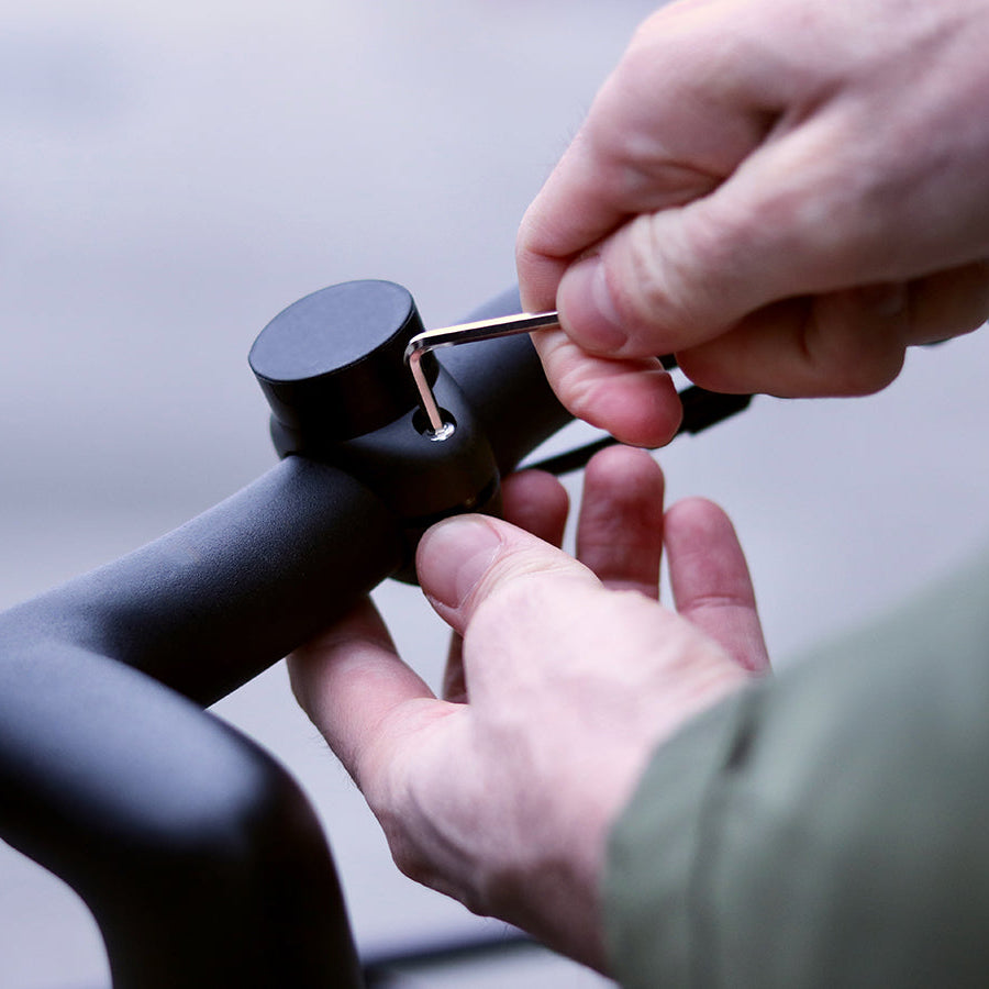 Uso de una llave Allen para atornillar el soporte magnético de teléfono Shapeheart en el manillar de la bicicleta