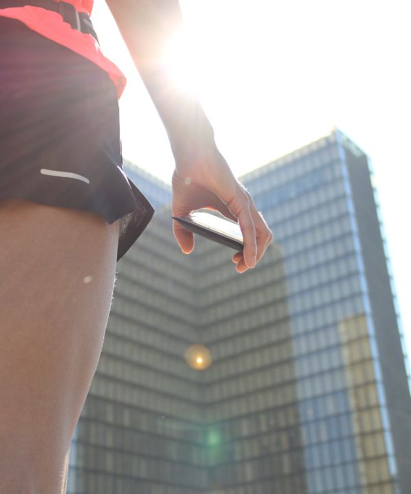 Corredora en ropa ligera corriendo al amanecer con un cinturón de running que contiene una pequeña botella, símbolo de la hidratación estival.