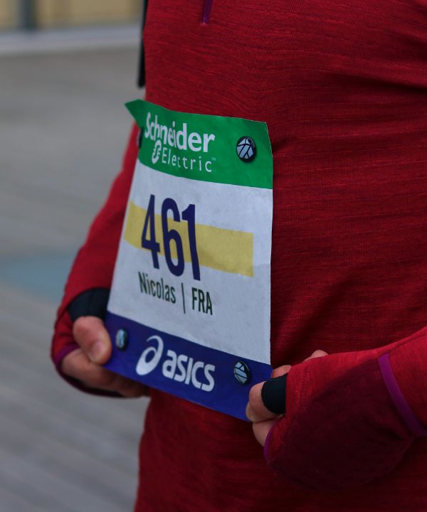 Atleta en la salida de una competición llevando un dorsal sujeto por imanes en una camiseta técnica, ilustrando la preparación óptima para una carrera oficial.