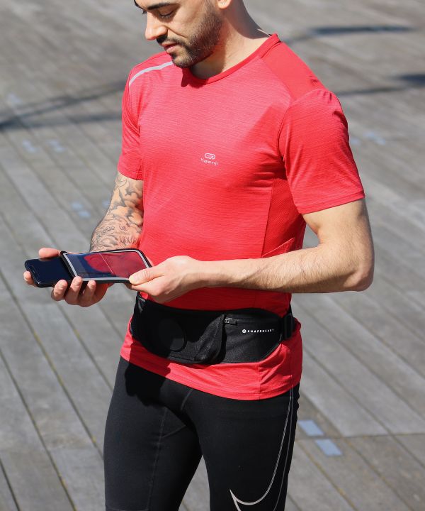 Corredor con chaqueta impermeable corriendo bajo la lluvia con un brazalete resistente al agua visible en el brazo, ilustrando la protección de los dispositivos electrónicos durante la carrera.