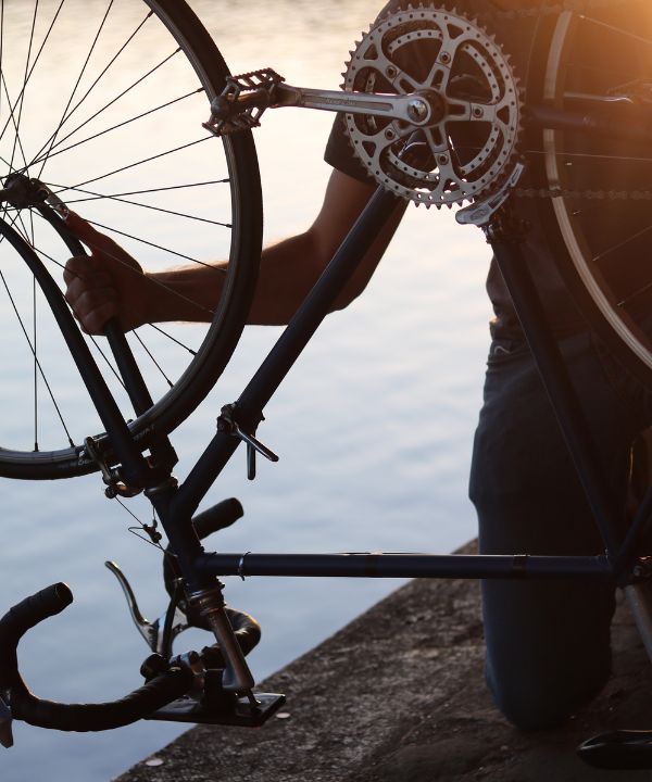 Ciclista deteniendo su bicicleta para reparar un pinchazo, con una minibomba y una cámara de aire a sus pies.
