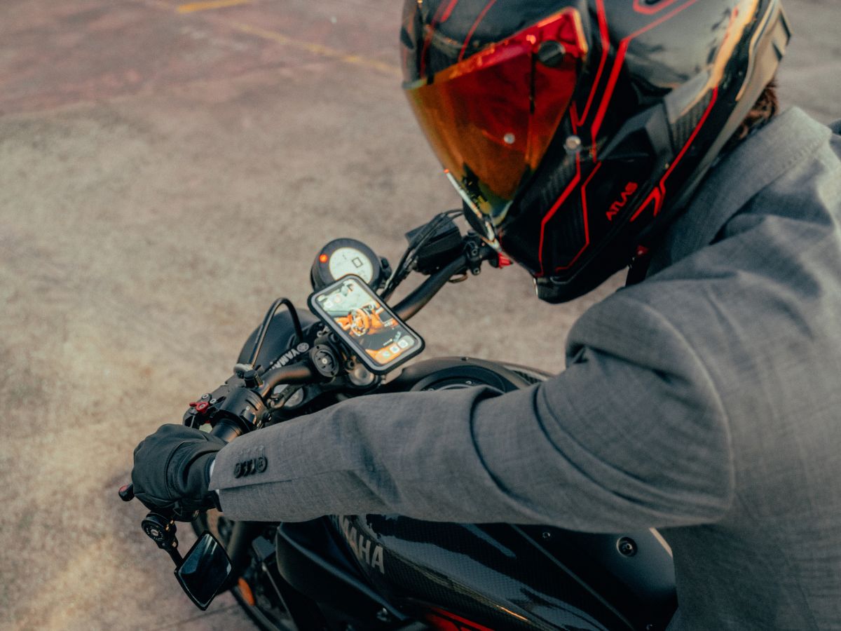 Contenido minimalista de una bolsa de motociclista: guantes, candado compacto, powerbank.