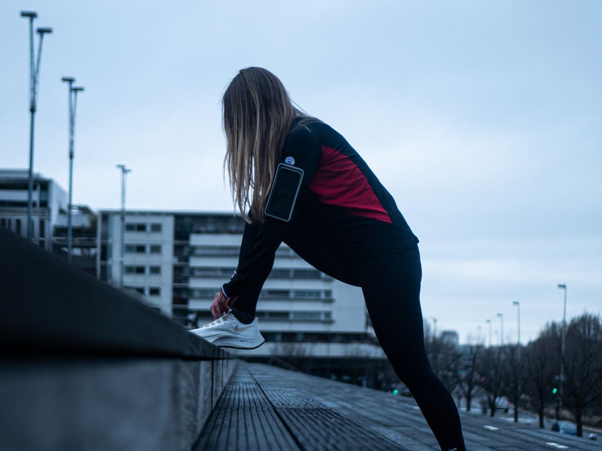 Runner escuchando música con auriculares inalámbricos durante un entrenamiento.