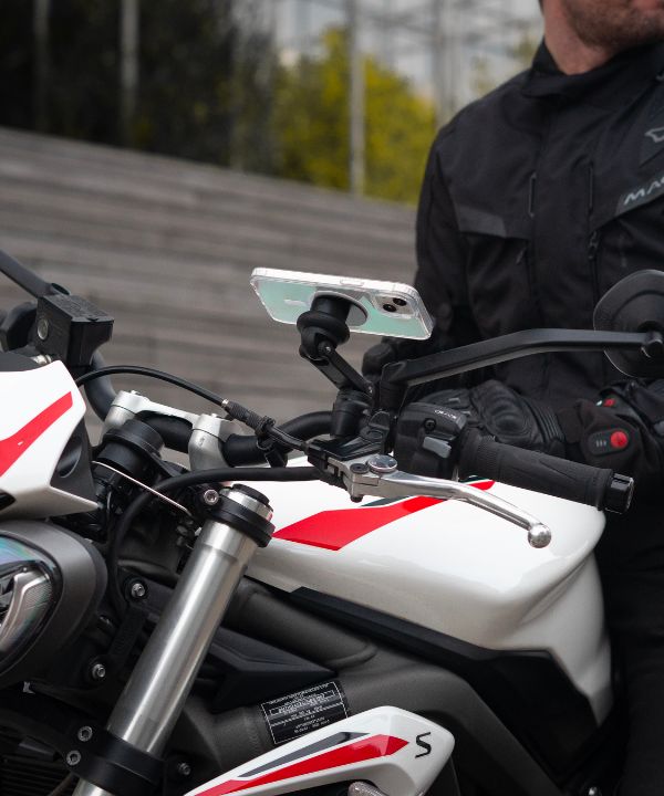 Un motociclista en la carretera mirando su espejo retrovisor para anticipar el tráfico a su alrededor. Una escena que refleja la importancia de una vigilancia constante en entorno urbano.