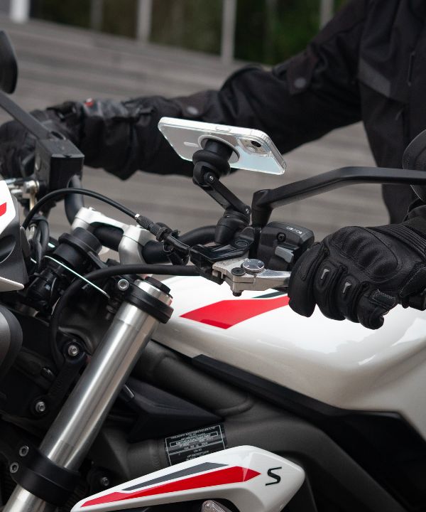 Un semáforo en rojo con un motociclista listo para arrancar, ilustrando la necesidad de dominar las salidas. La postura del motociclista muestra su concentración antes de retomar la carretera.