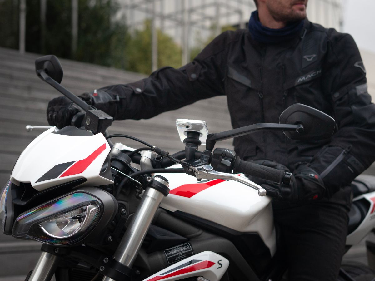 Un motorista con una chaqueta reflectante con su luz encendida, ilustrando la importancia de ser visible. La imagen insiste en el equipamiento de seguridad para reducir el riesgo de accidentes.