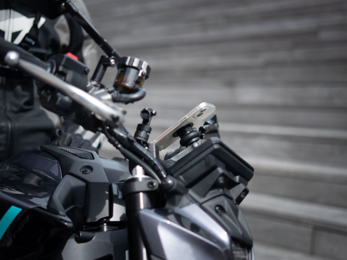 Teléfono fijado en un soporte Shapeheart en moto con pasajero, GPS visible, seguridad y accesibilidad máximas.