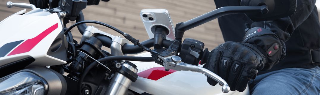 Motociclista principiante sosteniendo su casco junto a su moto, ilustrando la elección decisiva de la primera motocicleta tras obtener el permiso A2.