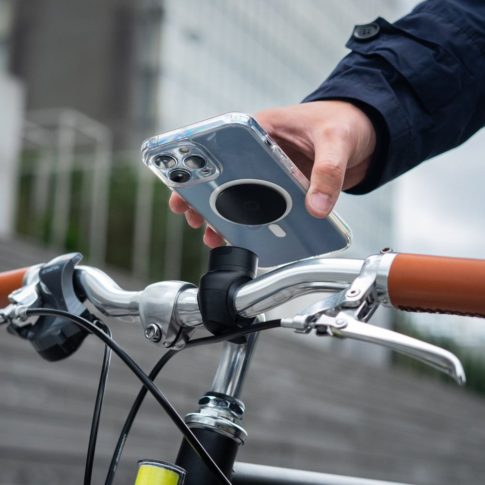 Smartphone equipado con una placa metálica Shapeheart, fijación snap en un manillar de bicicleta urbana.