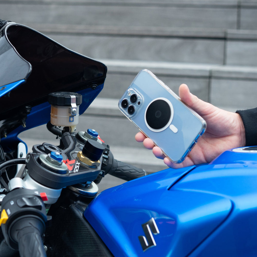 Smartphone con placa metálica Shapeheart sujeto frente al manillar de una moto deportiva
