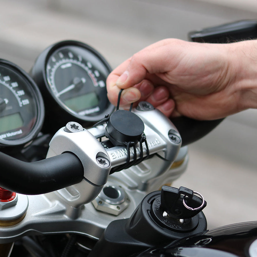 Correa elástica Shapeheart para moto - fijación segura. Vista en situación que demuestra la instalación de las correas en un manillar de moto, perfecta para mantener el soporte en su lugar.