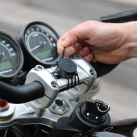 Correa elástica Shapeheart para moto - fijación segura. Vista en situación que demuestra la instalación de las correas en un manillar de moto, perfecta para mantener el soporte en su lugar.